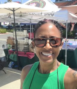 House of Mosaic Candles founder Toni Shaw smiling at an outdoor vending and community event in Los Angeles.