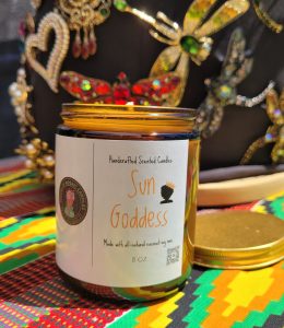 Sun Goddess scented candle by House of Mosaic Candles displayed on colorful cultural-inspired fabric.