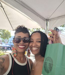 Customer shopping at the House of Mosaic Candles booth during a local pop-up event.